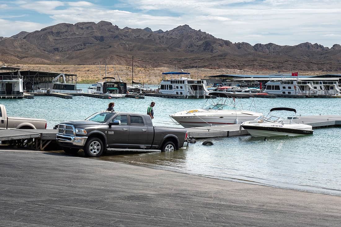 A boat trailer backed down a launch ramp into the water