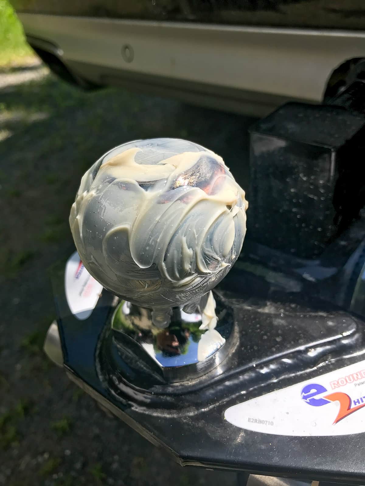 A greased trailer hitch ball on a mount, photographed close up