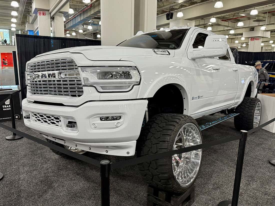 A lifted pickup truck on large wheels at a show stand
